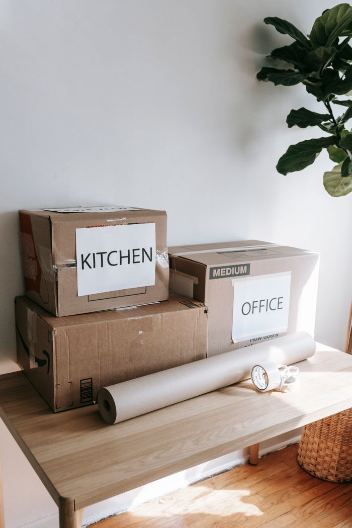 services-02 Cardboard boxes labeled for kitchen and office on a wooden table indicating moving day.